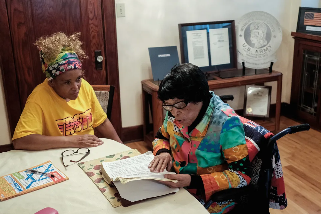 two woman sit a kitchen table reading together
